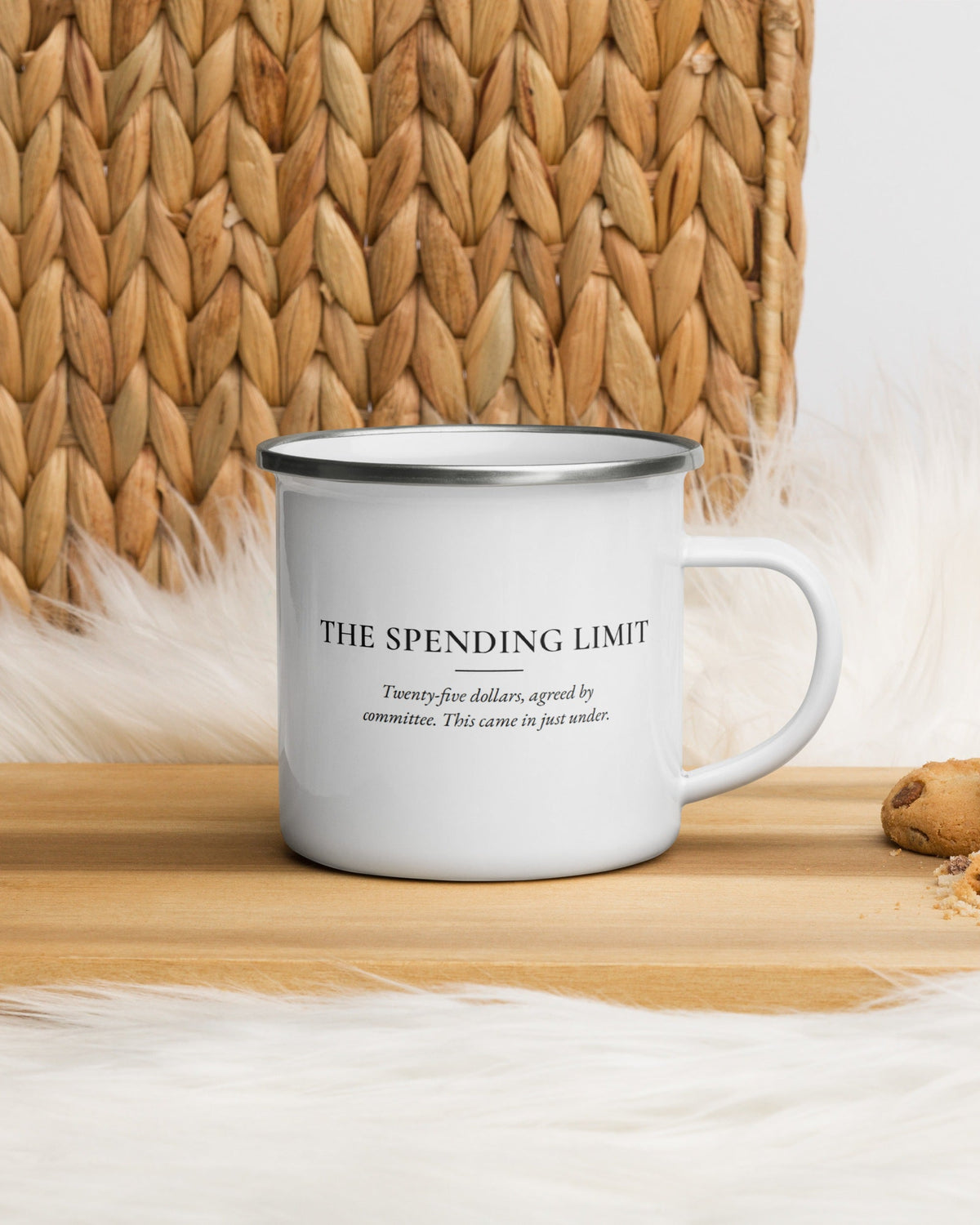 The Spending Limit enamel mug on a wooden table by a jute basket