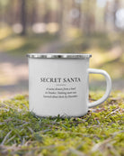 The Secret Santa enamel mug on moss in a forest