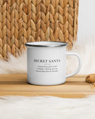 Secret Santa enamel mug on a wooden table by a jute basket